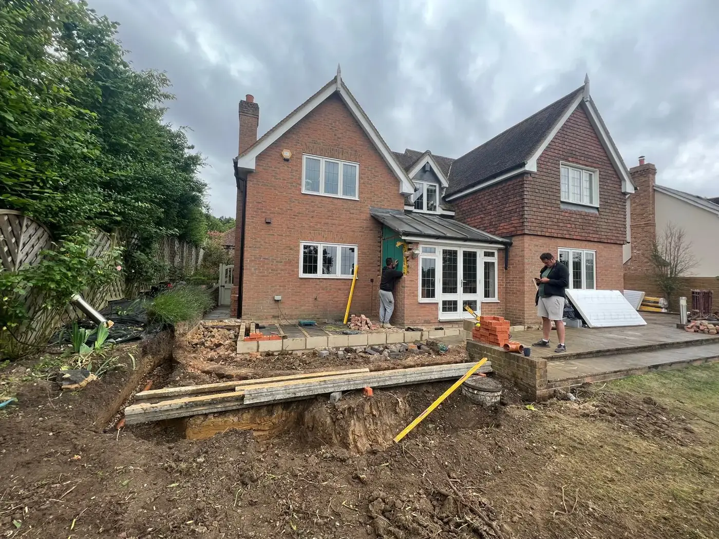 House extension under construction with foundation trenches and materials on site